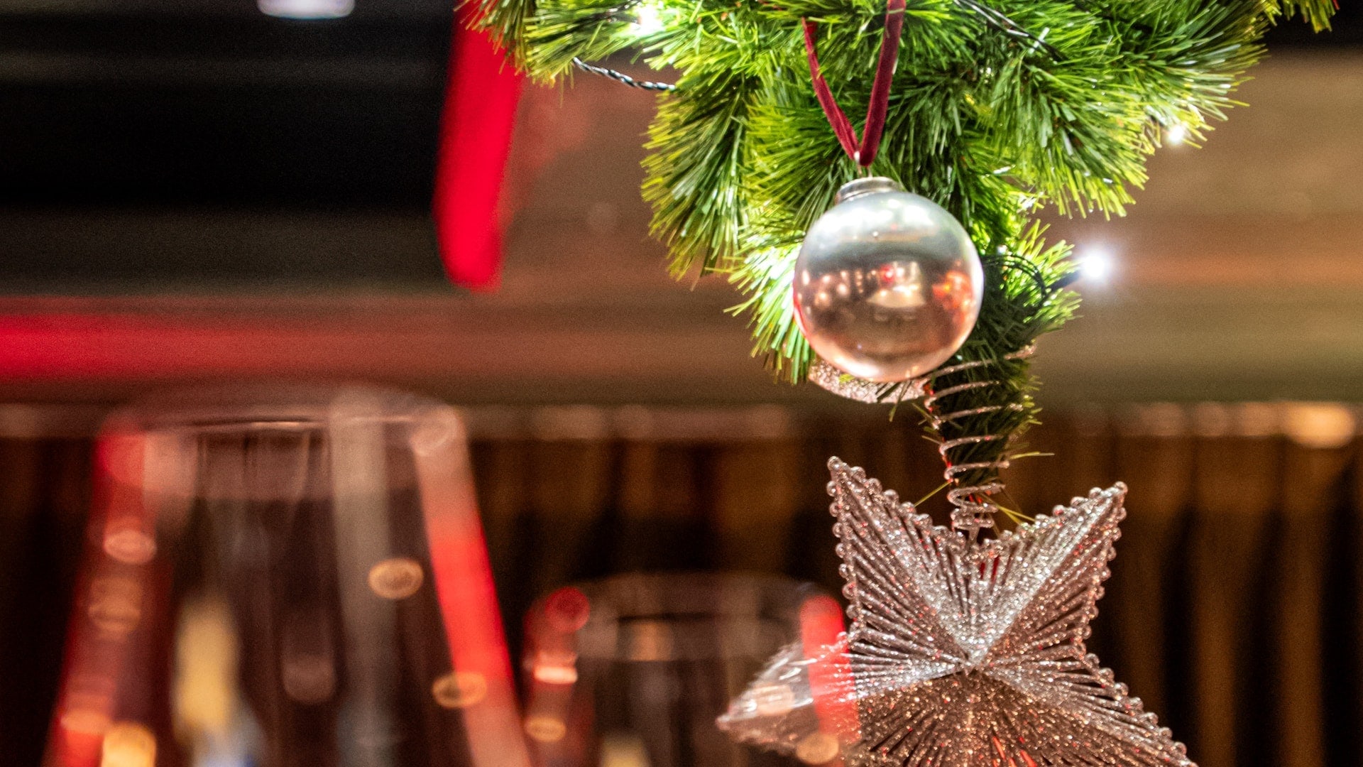 Close-up of the upside-down Christmas tree at Bisou, a modern French restaurant on Soi Langsuan in Bangkok, a silver bauble on a red ribbon and the star hanging from the ceiling, photographed at Christmas 2025