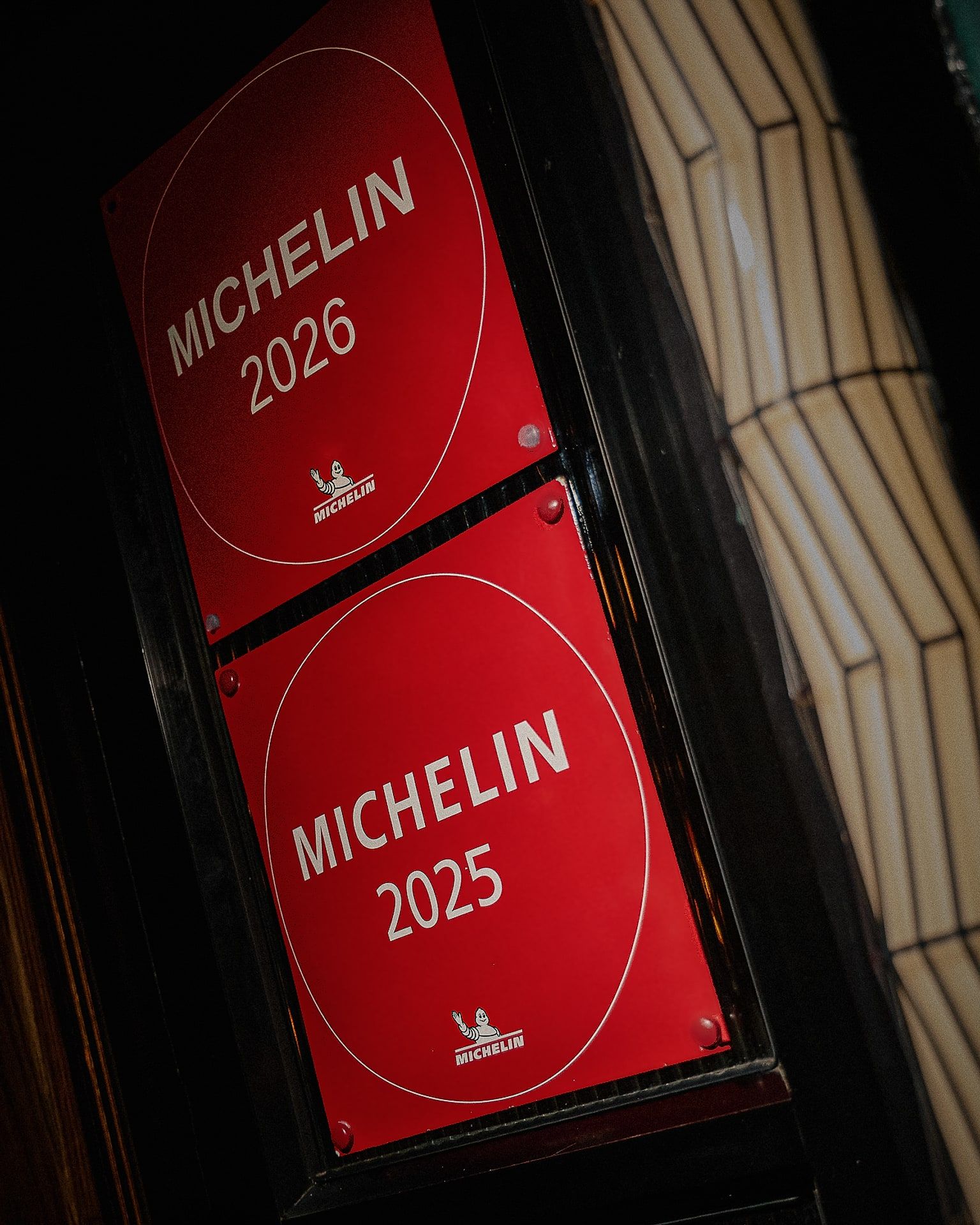 The MICHELIN Guide 2026 and 2025 plaques at the entrance of Bisou, a modern French restaurant on Soi Langsuan in Bangkok