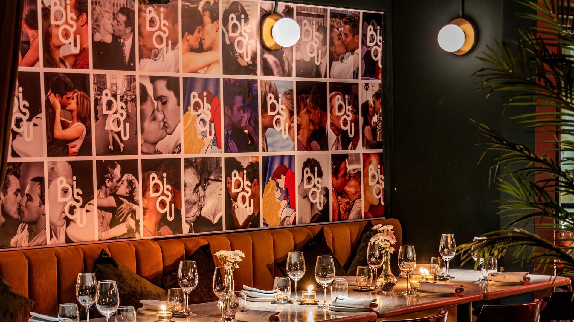 Candlelit tables in front of the kiss wall at Bisou, a modern French restaurant on Soi Langsuan in Bangkok