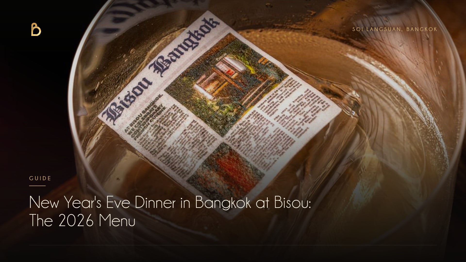 The New Year's Eve cover for Bisou Bangkok, a modern French restaurant on Soi Langsuan: an amber cocktail over a large clear ice cube printed with the Bisou Bangkok wordmark, on a wooden tray in the dark bar